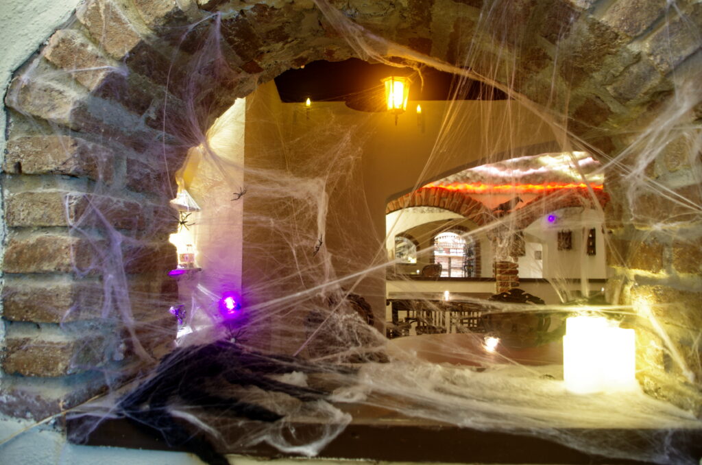 Detail na okno ozdobené pavučinami v kouzelnickém baru